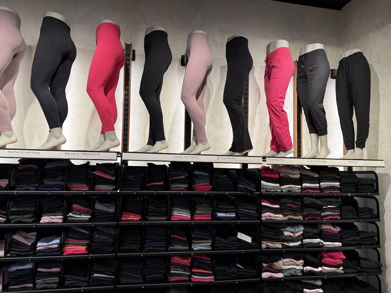 Zur Schau gestellte Sportleggings in verschiedenen Farben über Regalen mit gefalteter Kleidung