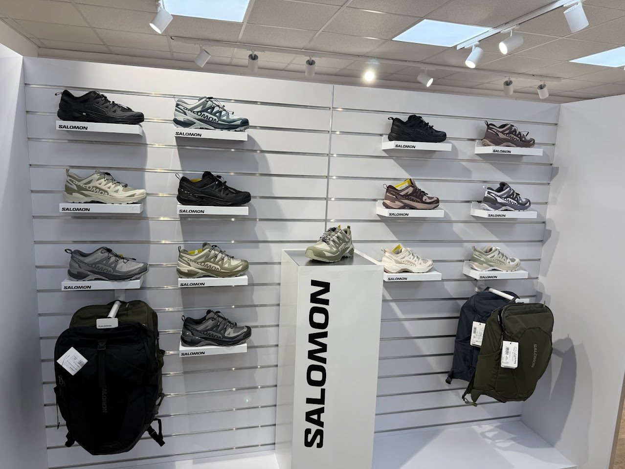 Eine Wand mit Modellen von Salomon-Sportschuhen und -Rucksäcken